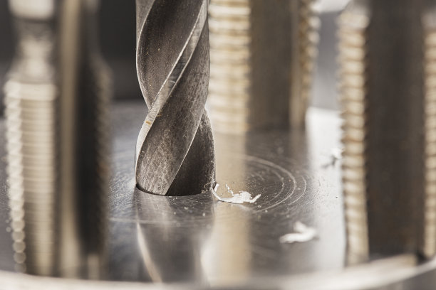 金属钻头用刨花在工业钻床上的铝坯上打孔。金属加工行业。多刀和立铣刀。图片下载