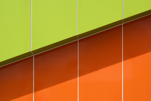 现代建筑外墙面充满活力的绿色和橙色铝复合瓷砖的背景和纹理，表面有阳光和阴影图片下载