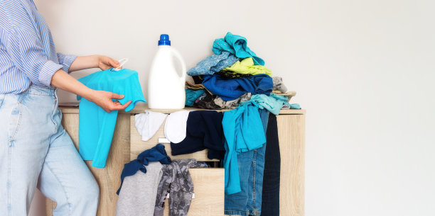 特写女人的手拿着一件彩色t恤，旁边是一个模型瓶子图片下载