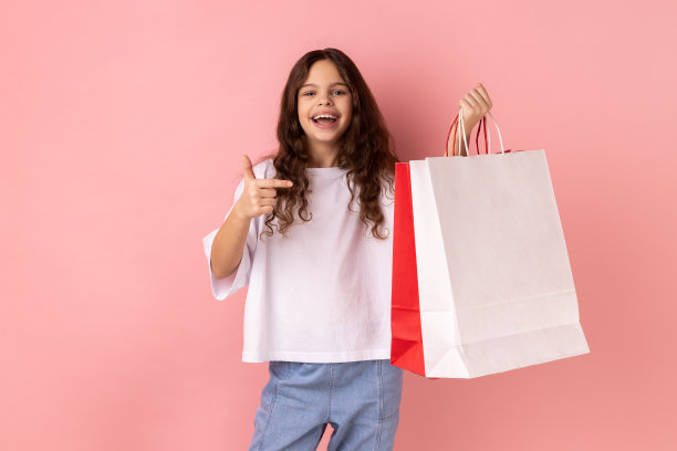 小女孩指着购物袋兴奋地看着镜头，脸上露出高兴快乐的表情图片下载