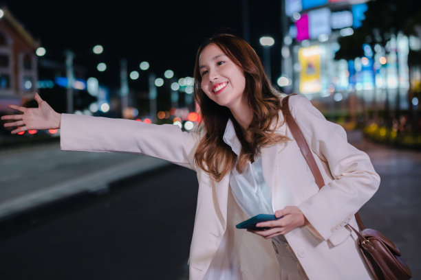 亚洲女商人晚上在城市的街道上用手机叫出租车图片下载