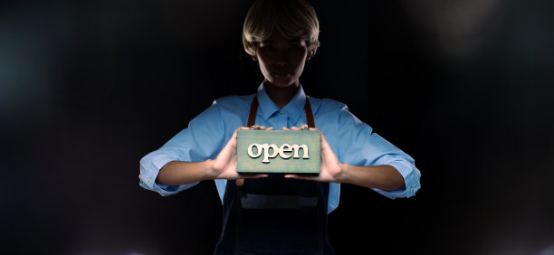 白种人开设招牌业务，在门口商店、咖啡厅、零售店、迎宾店等展示服务。快乐企业家女性金色头发穿服务员服装作为开放营业时间的概念图片下载