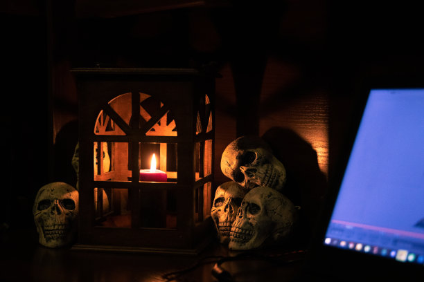 万圣节房间内部工作空间与笔记本电脑照明屏幕和背景中心组成场景与蜡烛在复古灯笼和装饰头骨图片下载