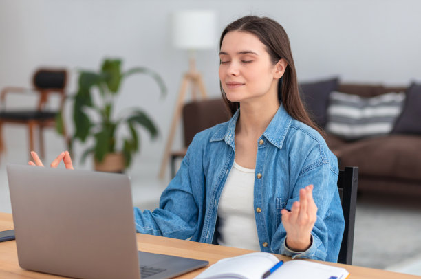 健康的生活方式。放松平静的年轻女子冥想休息后，坐在办公室的工作场所辛苦的工作，闭上眼睛，保持在瑜伽姿势的手图片下载