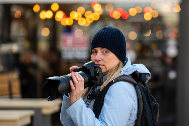 金发中年女性晚上拿着相机走在城市街道上，生活理念图片下载