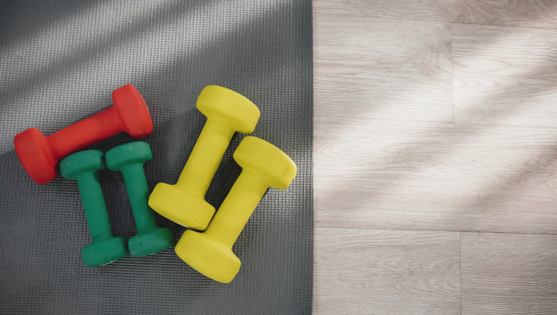 运动器材概念，小哑铃放在地板上的运动垫上，平视。图片下载