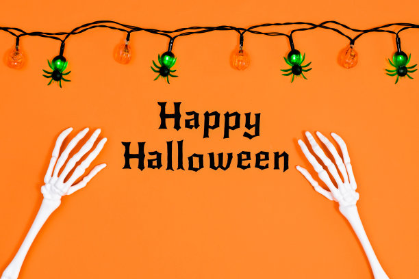 万圣节快乐文字与骷髅手和灯笼在橙色的背景。平躺图片下载