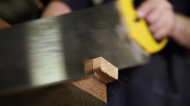 手工概念，木工车间。木匠用手锯锯木板。特写镜头。图片下载