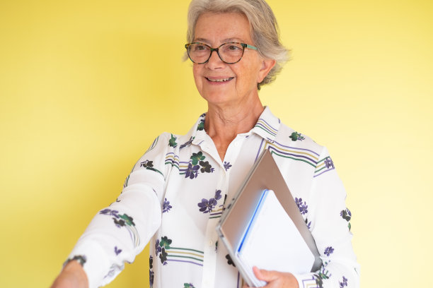 有吸引力的成熟商业女性与手提电脑在手颤抖的手，孤立的黄色背景图片下载