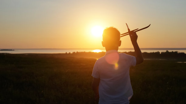 少年在草地上奔跑，直到日落发射飞机图片下载