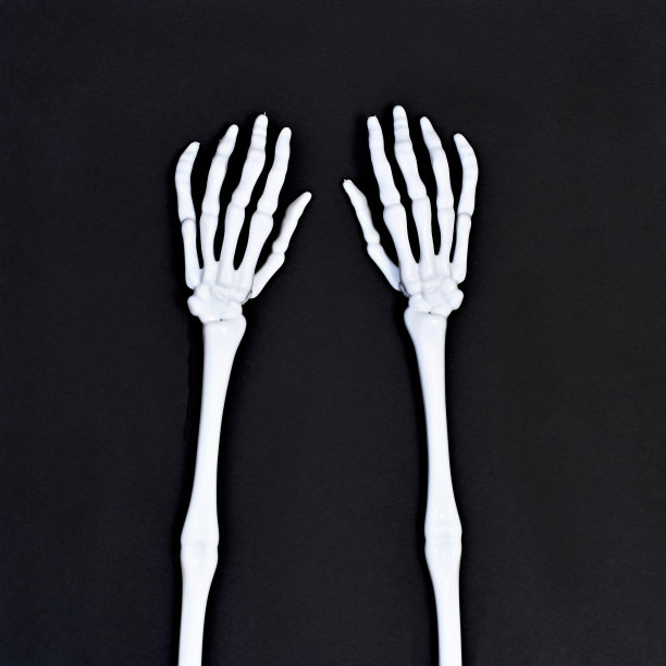 毛骨悚然的骷髅手在万圣节的黑色背景上。平的。创意秋季假期概念。图片下载