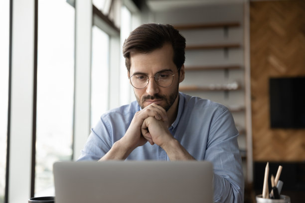 有思想的专注的商人在笔记本电脑工作的眼镜图片下载