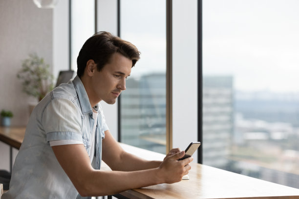 专注的千禧一代男人在智能手机上使用在线应用图片下载
