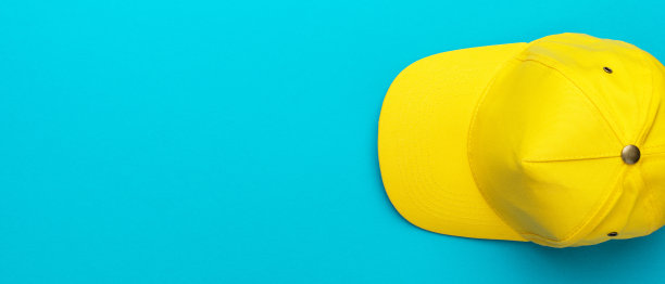 顶视图的黄色棒球帽在蓝色蓝绿色的背景与复制空间图片下载