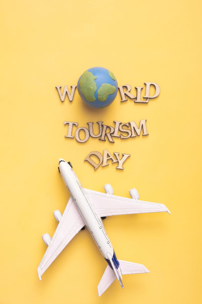 世界旅游日的文字来自木制字母，黄色背景为地球仪和飞机。俯视图，平铺图片下载