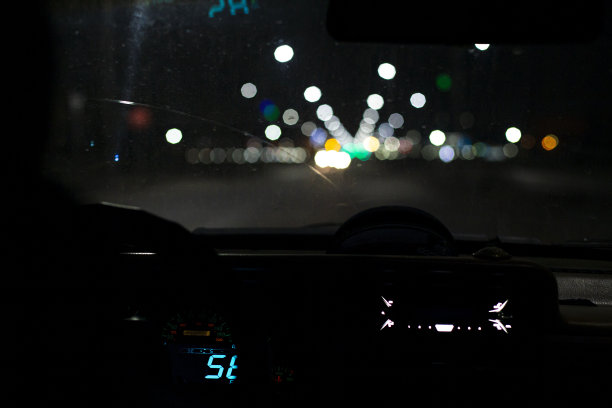 在车内的雾灯照射下，从乘客舱看夜间道路，路面潮湿，玻璃肮脏，能见度很低。前后背景模糊与散景效果图片下载