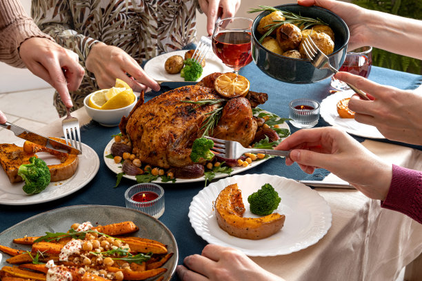 人们庆祝感恩节。感恩节聚会餐桌摆设。传统节日的烤鸡大餐和蔬菜。家庭聚会或聚会。图片下载