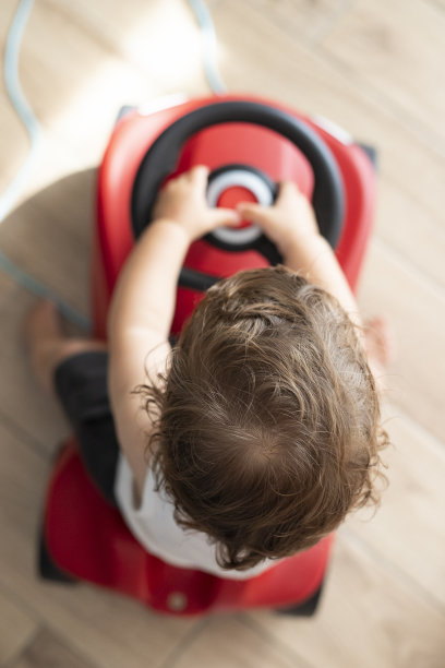 小男孩在玩手推车。顶视图,室内。图片下载