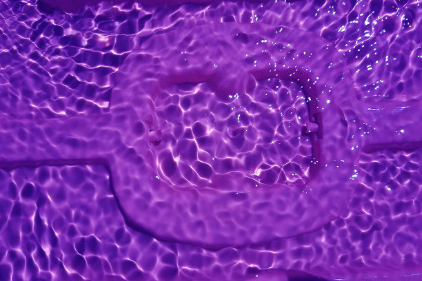 散焦模糊透明紫色清澈平静水面纹理与飞溅和气泡。时髦的抽象自然背景。阳光下的水波与复制空间。紫色的水彩纹理图片下载