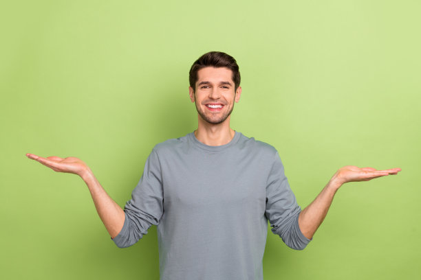 可爱的年轻深色小伙的照片抱空穿灰色衬衫孤立在绿色的背景图片下载