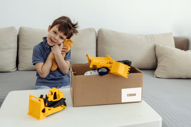 捐赠的概念。男孩手里拿着捐赠箱，里面有玩具和一些衣服。副本的空间。图片下载