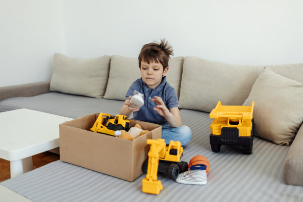 一个男孩拿着一个箱子，里面装着捐赠的玩具和衣服。旧玩具放入捐赠箱，再利用再循环利用。一名男孩正在打包捐赠衣物。图片下载