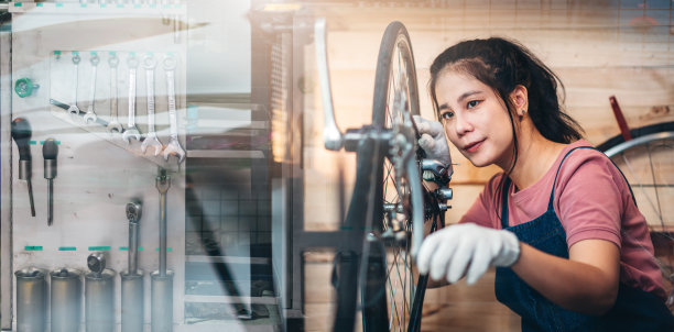 美丽的亚洲女子修理工女孩，用快乐的自行车维修和更换自行车链条，在家里自己的自行车车间。图片下载