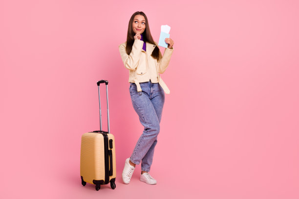 全身照片的聪明漂亮的女士与旅行箱持有票抬头穿夹克牛仔裤靴子孤立在粉红色的背景图片下载