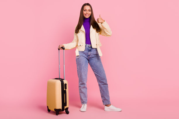 全身照片时髦的年轻女士与包大拇指向上穿现代布料孤立在粉红色的背景图片下载