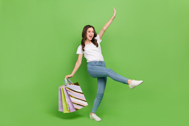照片时髦兴奋的年轻女士穿白色t恤走购物者孤立的绿色背景图片下载