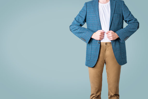 穿着蓝色夹克，米色裤子，蓝色背景的男人图片下载