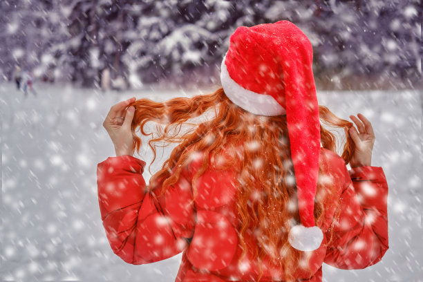 一个幸福的女人站在那里，手里拿着一把红色的伞，一个冬天的公园，树被雪覆盖着图片下载
