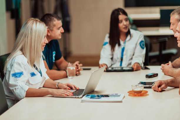 一群保安坐在系统控制室里做简报他们在安全数据中心工作，周围是多个屏幕图片下载