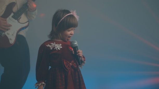 穿着复古礼服的小女孩在舞台上唱歌，她的父亲在弹奏电吉他图片下载