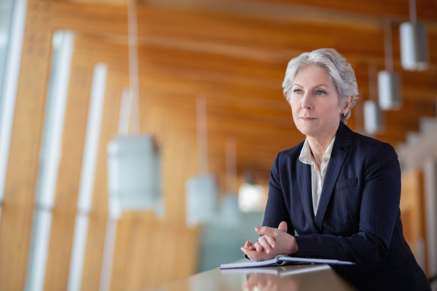 高级高加索女商人的肖像靠在栏杆上的办公室阳台，双手紧握望向别处图片下载