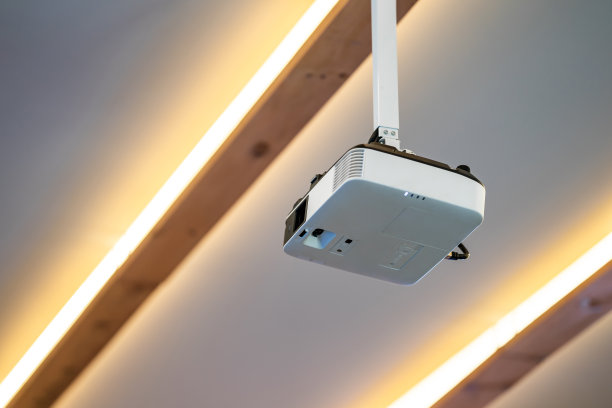 白色投影仪挂在会议室中央的天花板上。图片下载