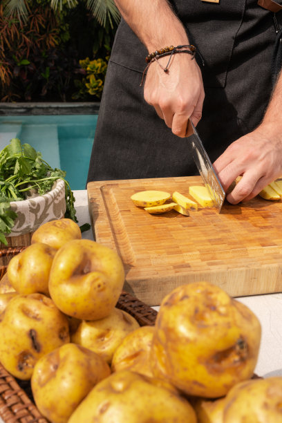 垂直裁剪的照片，一个人在木板上切土豆图片下载