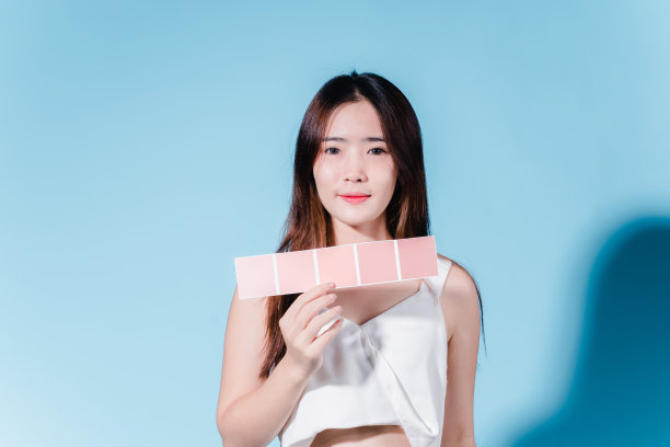 迷人的亚洲美女持有防晒霜和颜色规模与防晒紫外线或防晒霜的蓝色背景图片下载