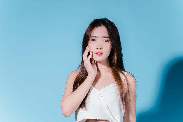 迷人的亚洲美女持有防晒霜和颜色规模与防晒紫外线或防晒霜的蓝色背景图片下载