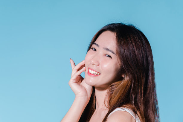 迷人的亚洲美女持有防晒霜和颜色规模与防晒紫外线或防晒霜的蓝色背景图片下载