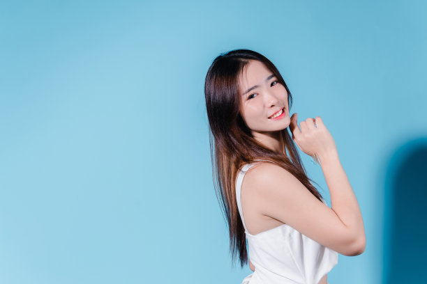 迷人的亚洲美女持有防晒霜和颜色规模与防晒紫外线或防晒霜的蓝色背景图片下载