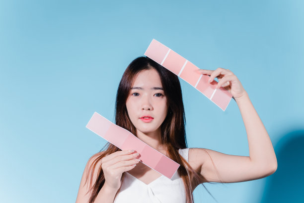 迷人的亚洲美女持有防晒霜和颜色规模与防晒紫外线或防晒霜的蓝色背景图片下载