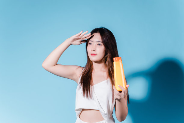 迷人的亚洲美女持有防晒霜和颜色规模与防晒紫外线或防晒霜的蓝色背景图片下载