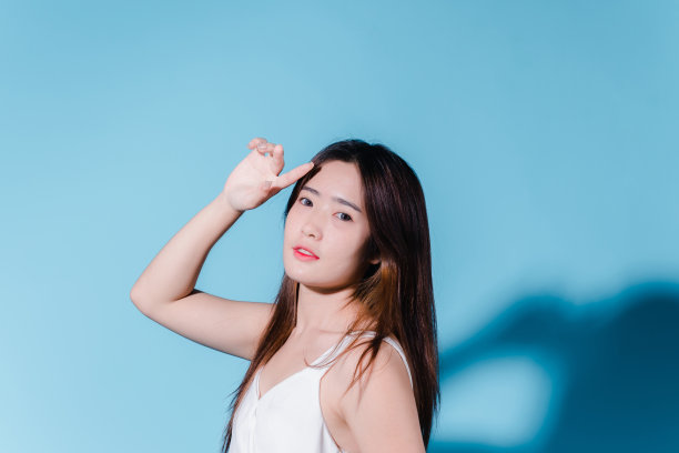 迷人的亚洲美女持有防晒霜和颜色规模与防晒紫外线或防晒霜的蓝色背景图片下载