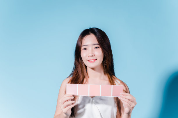 迷人的亚洲美女持有防晒霜和颜色规模与防晒紫外线或防晒霜的蓝色背景图片下载