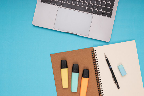 笔记本电脑，记事本，铅笔，橡皮，彩色铅笔。回到学校。孤立的蓝色背景图片下载