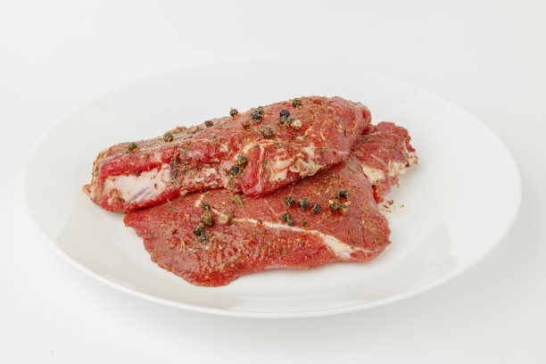 白盘子里的一块腌过的烤肉。图片下载