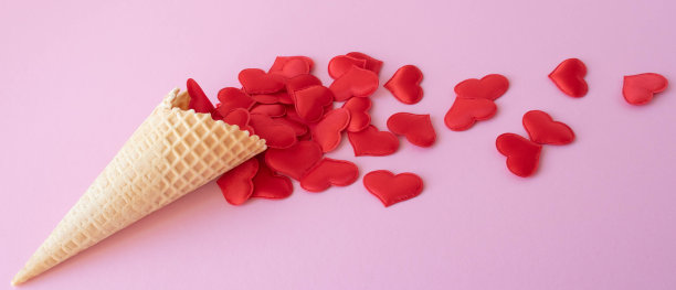 粉色背景上散落着红心的空华夫饼筒的创意照片。爱情的概念，夏天，春天图片下载