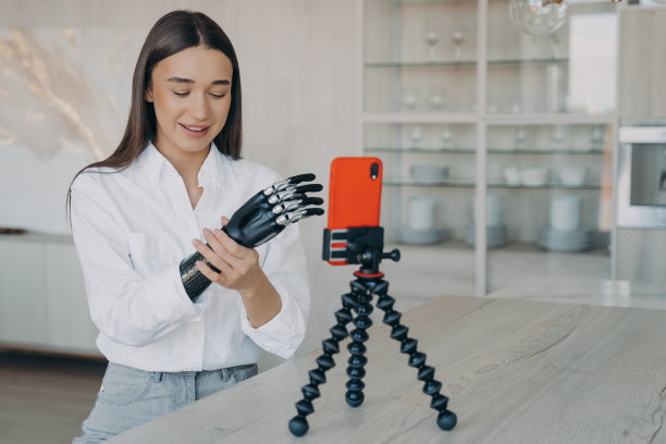 截肢者正在拍摄如何安装网络手臂的视频。迷人的残疾女孩是博主。图片下载