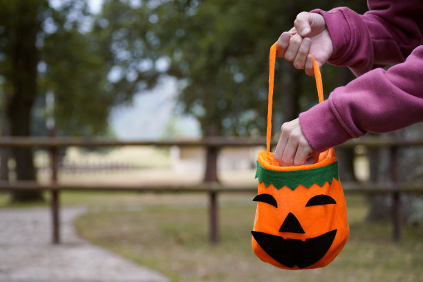 一个女人从万圣节的南瓜里取出糖果。有选择性的重点图片下载